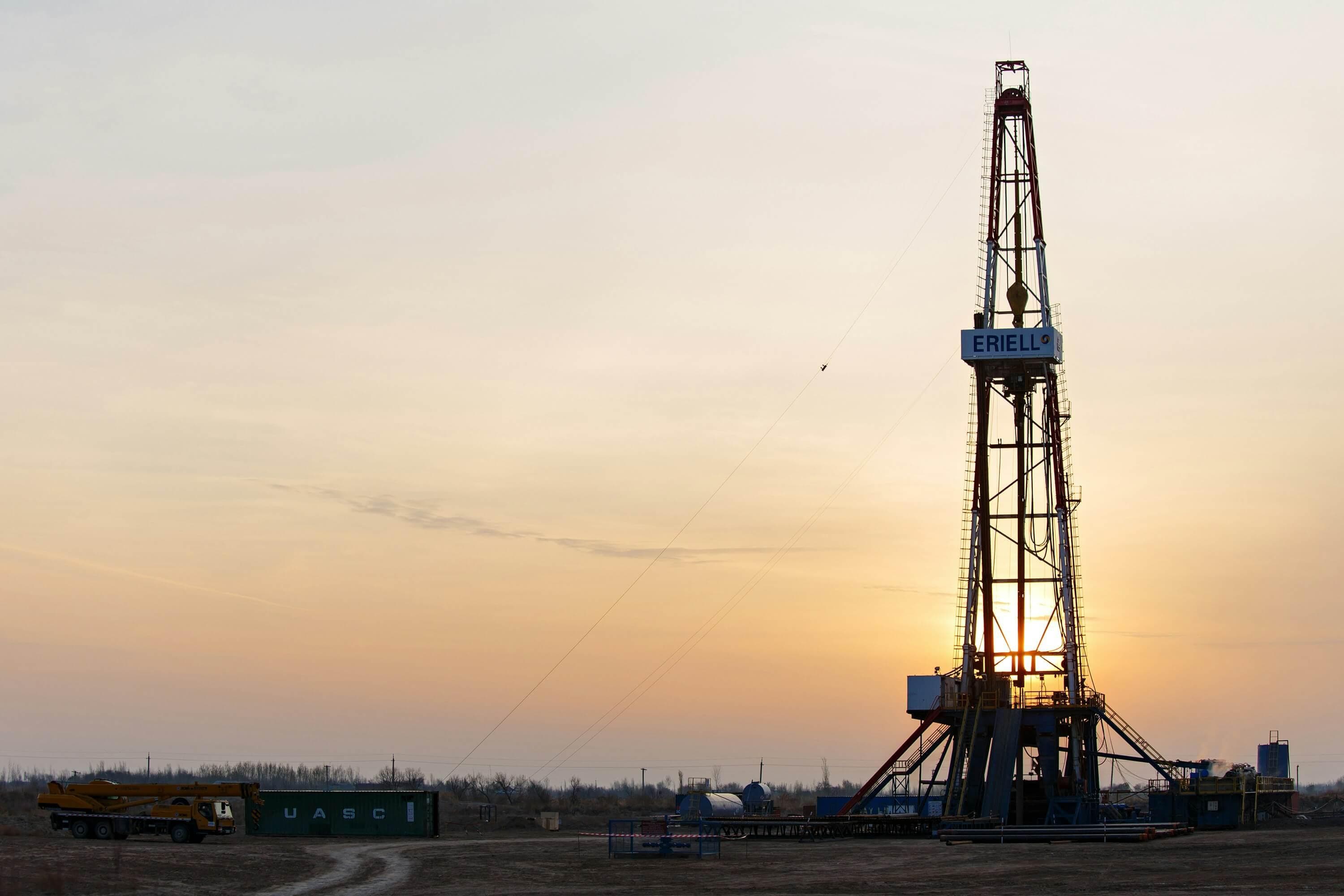 An oil rig with the sun setting behind it.